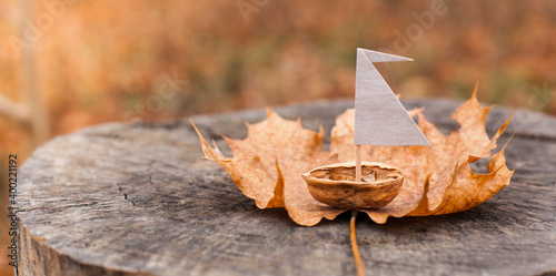 Small boat made from nutshell on autumn leaf.
Kleines Boot aus Nussschale auf einem Herbstblatt.