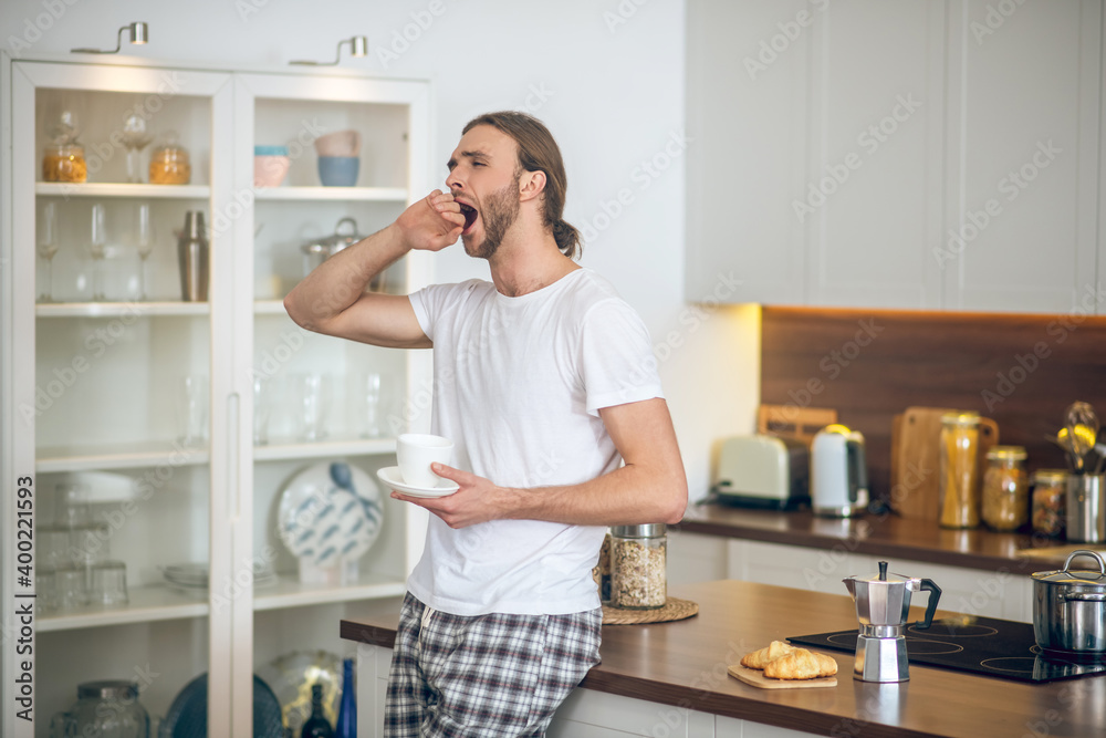 Young man in homewear having coffee in the kitchen Young man in homewear having coffee in the kitchen
