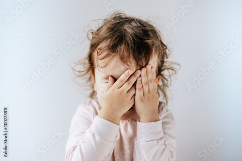 a child on a white background covered his eyes with his hands, afraid, emotions.