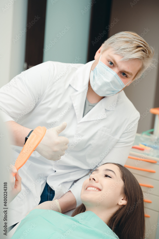 Girl in a chair looking at her teeth with dantes after the procedure Girl in a chair looking at her teeth with dantes after the procedure