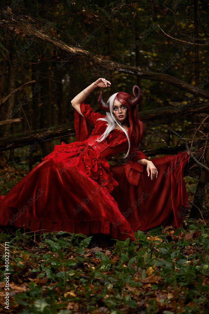 Stylish and fashionable model girl in the image of Maleficent posing among mystic forest - fairytale story, cosplay. Halloween