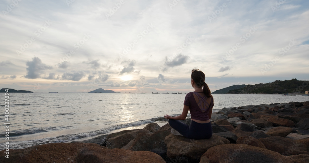 Fototapeta premium Woman do yoga and sit beside the sea