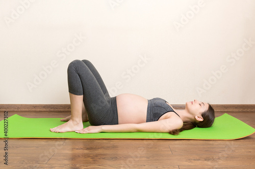 Pregnant woman meditating while sitting in yoga position. Meditating on maternity Pregnancy Yoga and Fitness concept at coronavirus time