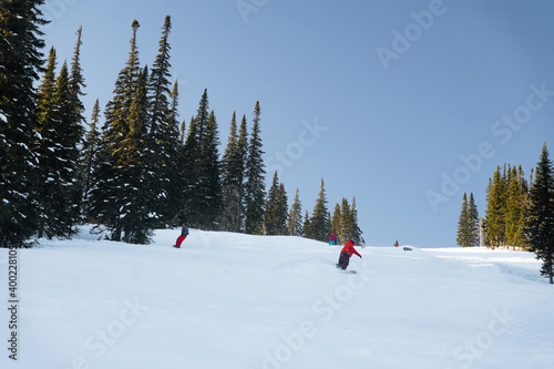 Skiers and snowboarders ride on a ski slope of a ski resort on a picturesque background of a snowy winter mountain