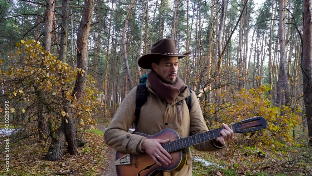 A backpacker with a guitar walks along a trail in the forest. Travel concept. 4K A backpacker with a guitar walks along a trail in the forest. Travel concept. 4K