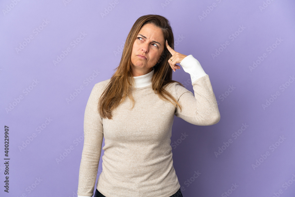 Middle age Brazilian woman isolated on purple background making the gesture of madness putting finger on the head Middle age Brazilian woman isolated on purple background making the gesture of madness putting finger on the head