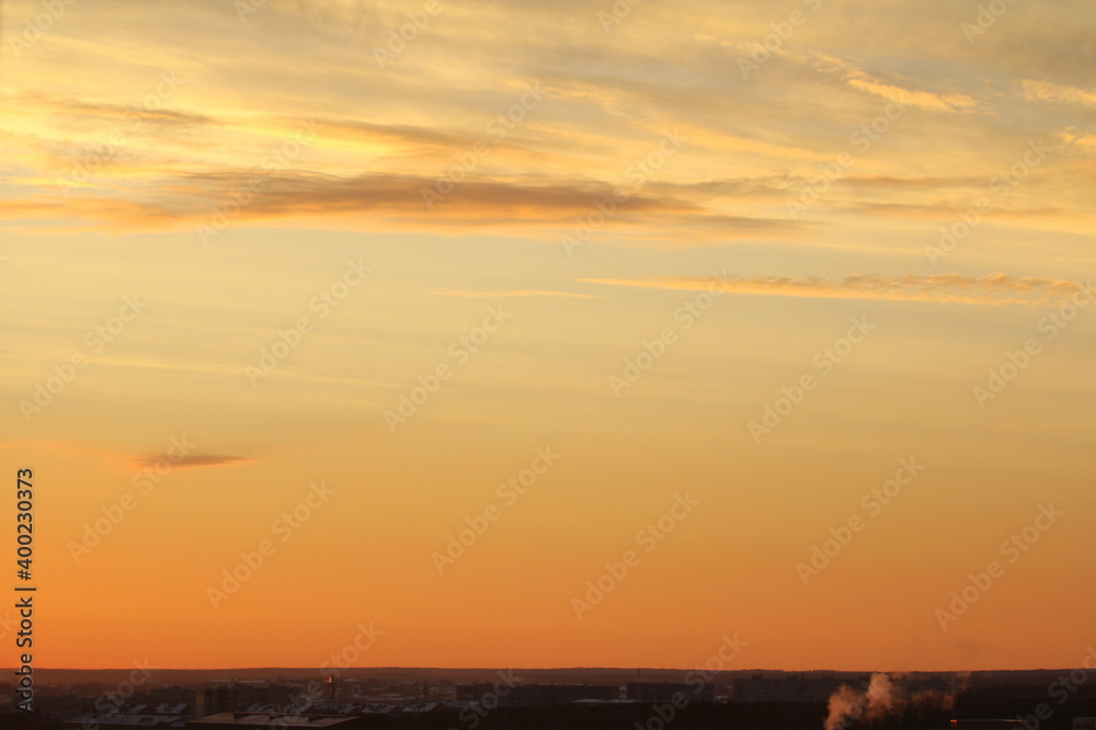 Fototapeta premium Sun below the horizon and clouds in the fiery dramatic orange sky at sunset or dawn backlit by the sun. Place for text and design
