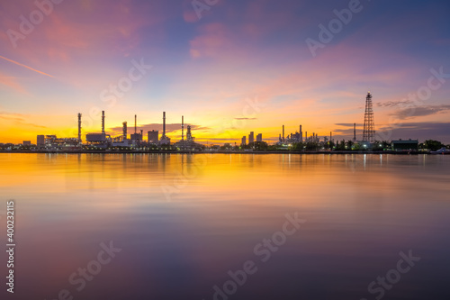 oil refinery plant chemical factory and power plant with many storage tanks and pipelines beside river at sunrise.