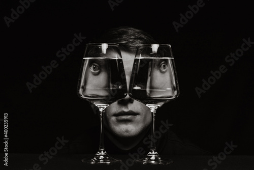 portrait of a strange man looking through two glasses of water photo