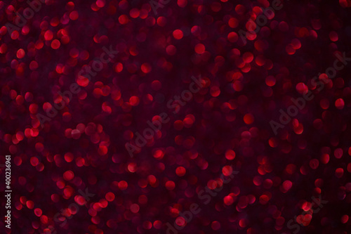 Festive red bokeh background. Shiny texture. New Year background. Defocused shiny sequins.