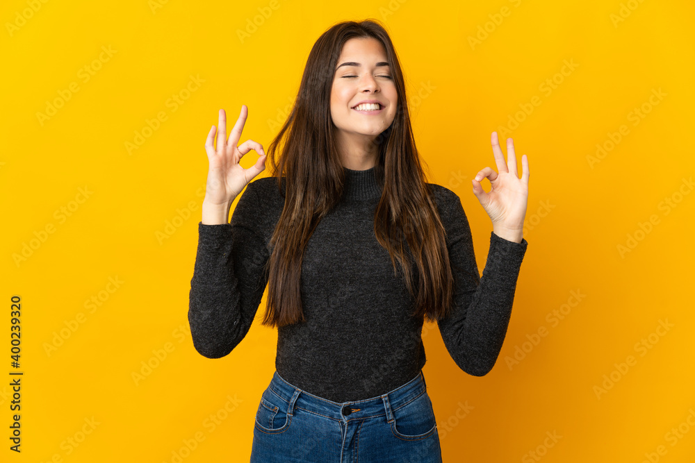Teenager Brazilian girl isolated on yellow background in zen pose Teenager Brazilian girl isolated on yellow background in zen pose