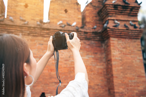 Asian woman traveling and photographing the city wall tha pae gate landmark of Chiang Mai Thailand photo