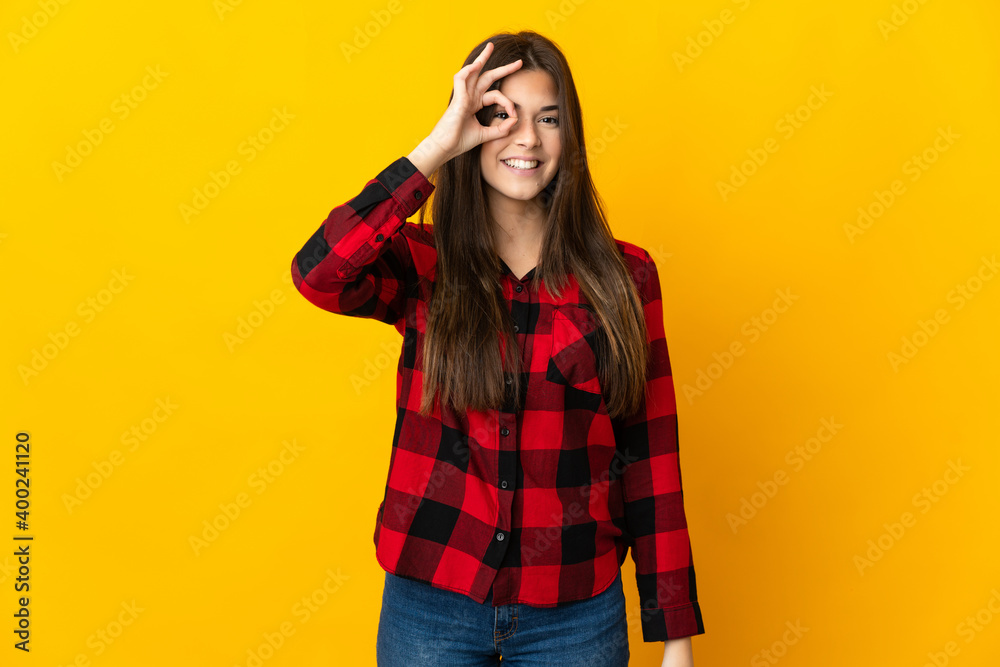 Teenager Brazilian girl isolated on yellow background showing ok sign with fingers