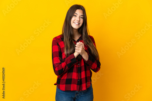 Teenager Brazilian girl isolated on yellow background laughing © luismolinero