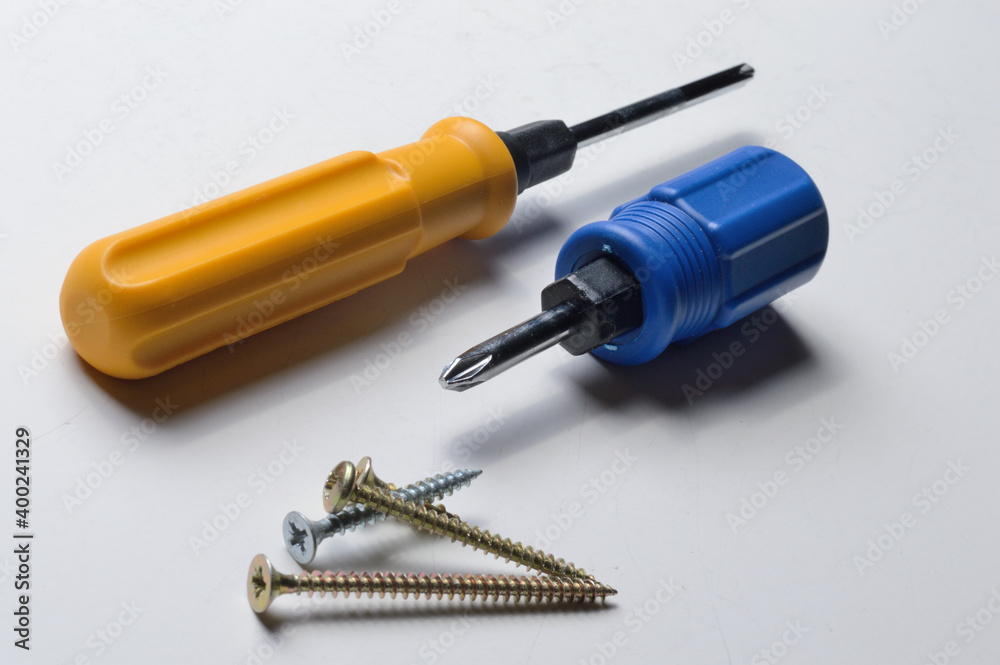 two different screwdrivers and several screws on a white background. close-up. two different screwdrivers and several screws on a white background. close-up.