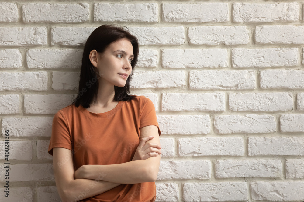 Charming youth. Confident millennial female standing near brick wall looking aside with light smile holding arms crossed. Young lady thinking pondering listening to someone with skepticism, copy space Charming youth. Confident millennial female standing near brick wall looking aside with light smile holding arms crossed. Young lady thinking pondering listening to someone with skepticism, copy space