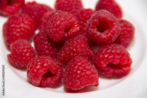 ripe red raspberries on a white plate