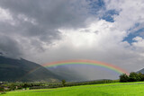 A large rainbow emerges from the clouds over an apple planted field in Val Venosta, Prato allo Stelvio, Italy