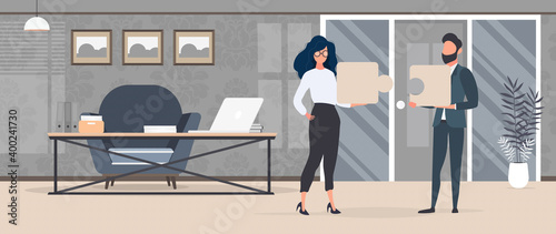 The guy and the girl are holding puzzle pieces. The woman and the man are putting together a puzzle. Office. The concept of teamwork, living together or understanding.