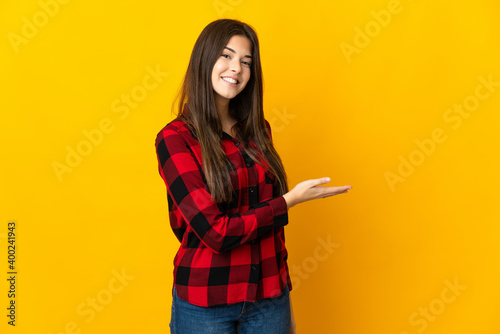 Teenager Brazilian girl isolated on yellow background presenting an idea while looking smiling towards