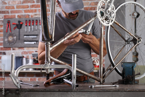 man repair the vintage bicycle in garage workshop on the workbench with tools, diy concept