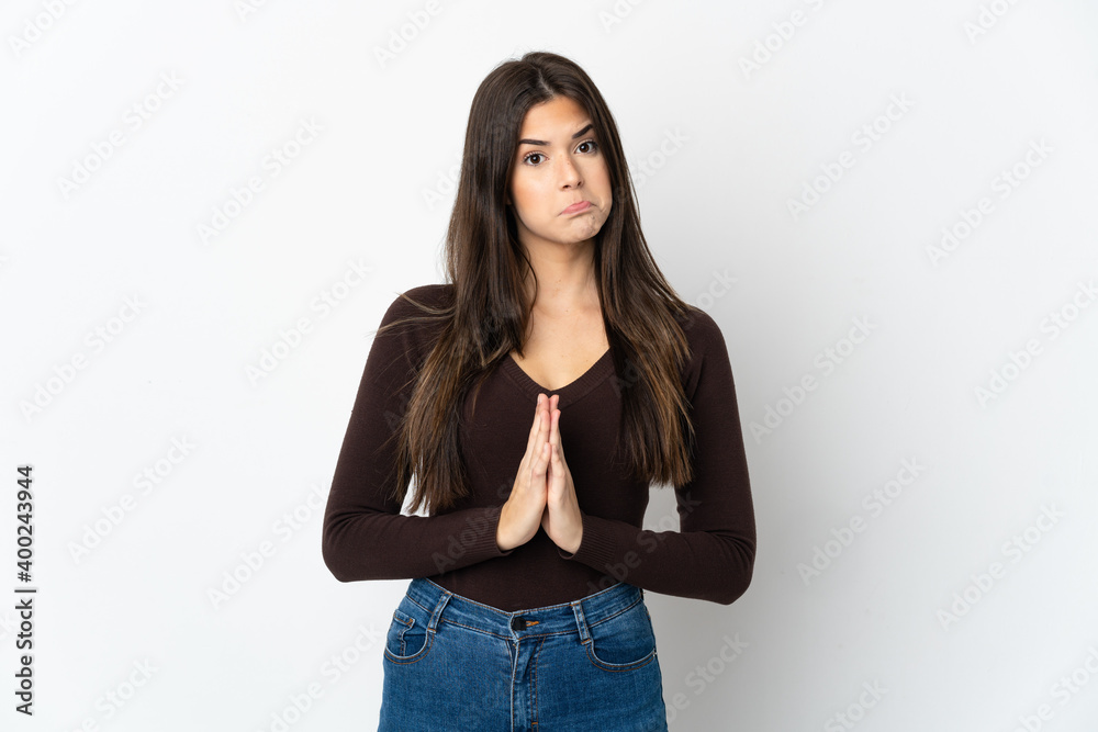 Teenager Brazilian girl isolated on white background keeps palm together. Person asks for something Teenager Brazilian girl isolated on white background keeps palm together. Person asks for something