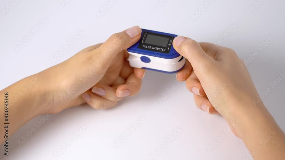 The person turns on and puts a pulse oximeter on his finger. A device for monitoring the pulse and oxygen in the blood. Self-diagnosis of health status. Close-up, white background. The person turns on and puts a pulse oximeter on his finger. A device for monitoring the pulse and oxygen in the blood. Self-diagnosis of health status. Close-up, white background.