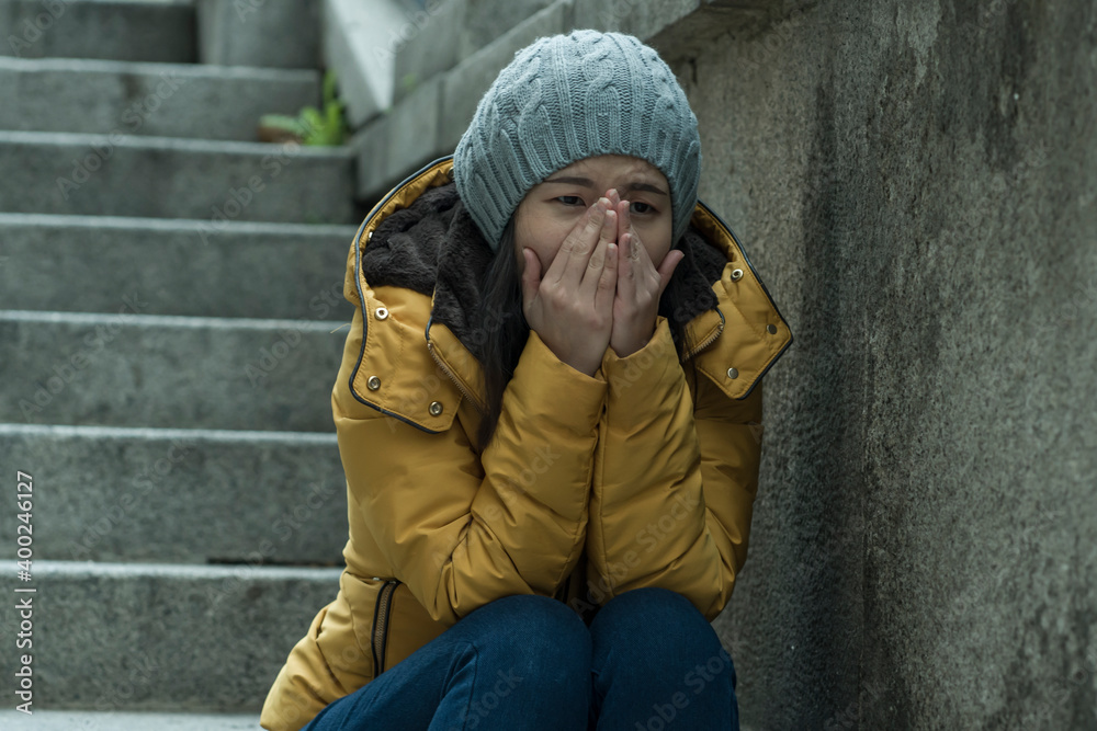 dramatic lifestyle portrait of young attractive sad and depressed Japanese woman in winter hat sitting outdoors on street corner staircase suffering depression problem crying dramatic lifestyle portrait of young attractive sad and depressed Japanese woman in winter hat sitting outdoors on street corner staircase suffering depression problem crying