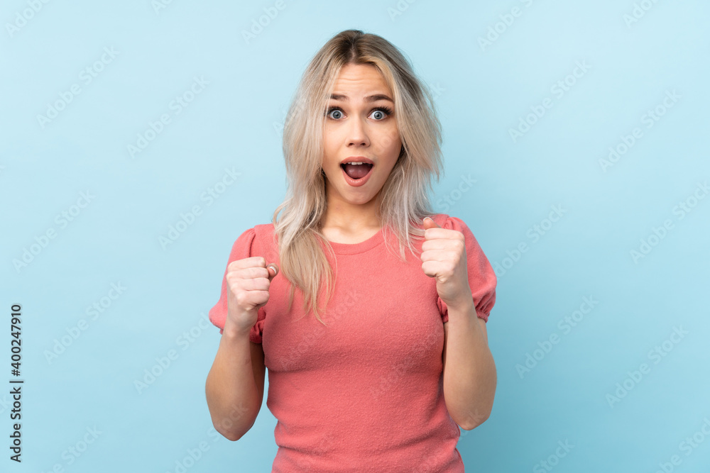 Teenager girl over isolated blue background celebrating a victory in winner position Teenager girl over isolated blue background celebrating a victory in winner position