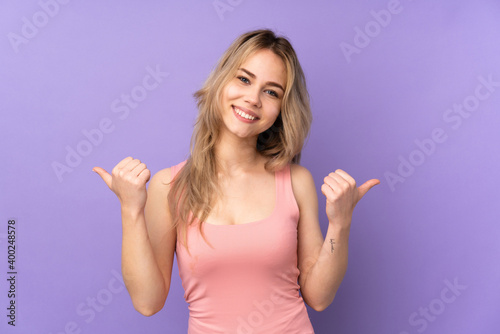 Teenager Russian girl isolated on purple background with thumbs up gesture and smiling