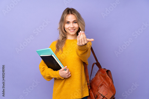 Teenager Russian student girl isolated on purple background inviting to come with hand. Happy that you came