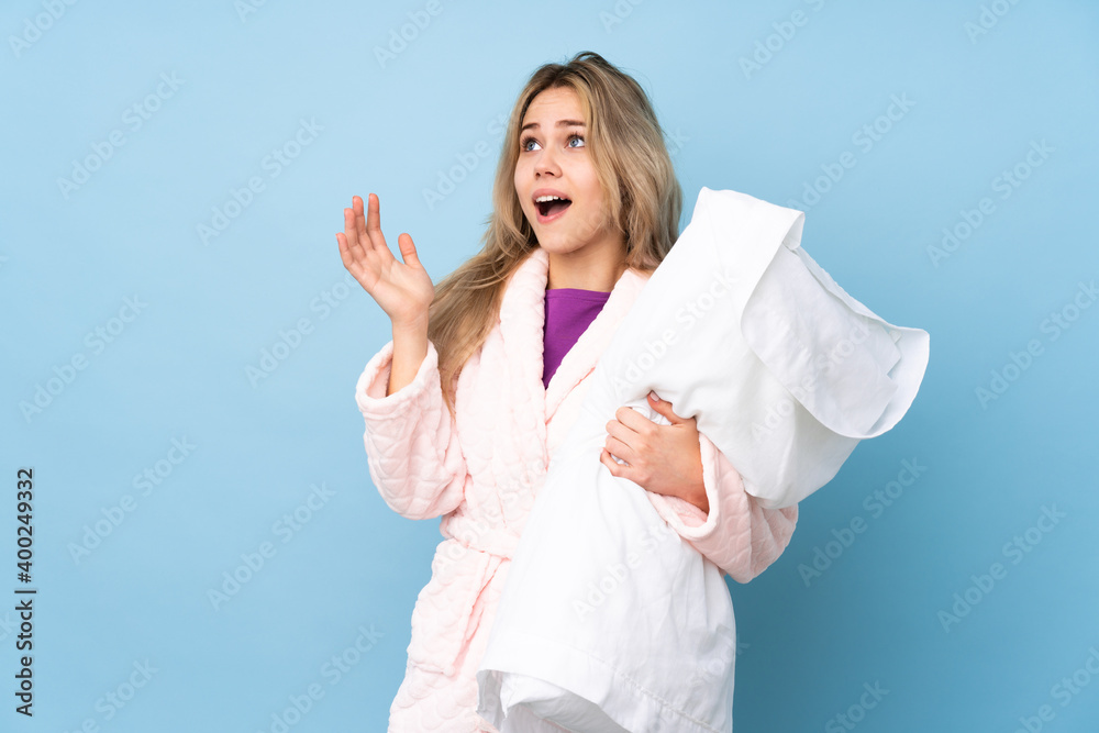 Teenager Russian girl in pajamas isolated on blue background with surprise facial expression Teenager Russian girl in pajamas isolated on blue background with surprise facial expression