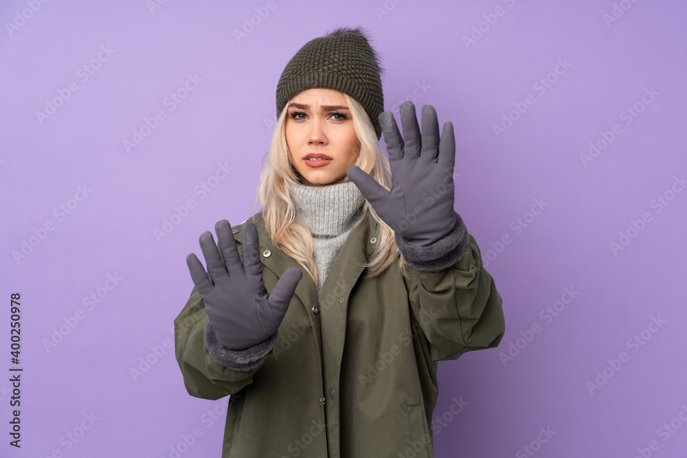 Teenager blonde girl with winter hat over isolated purple background nervous stretching hands to the front Teenager blonde girl with winter hat over isolated purple background nervous stretching hands to the front