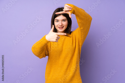 Young Ukrainian teenager girl over isolated purple background focusing face. Framing symbol © luismolinero