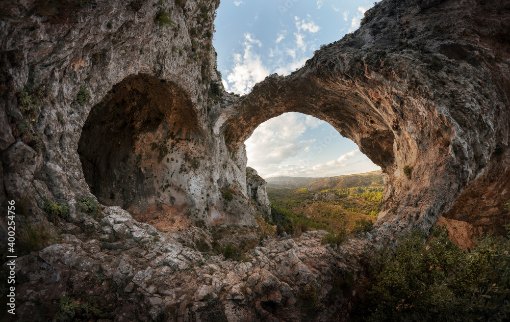 The heart of the mountain. Panoramic of a heart carved in a mountain. An ancient cave and a rock arch form the image of a stone heart. Landscape of a sunset and a heart carved in the mountain. 
