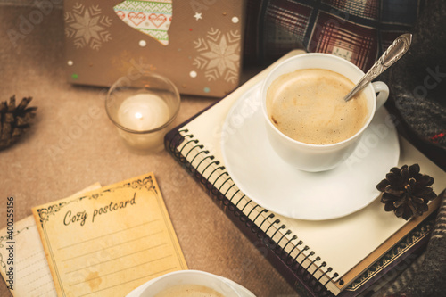 Cozy evening, mood and a cup of warm coffee on a plaid with decorations, a candle, a postcard