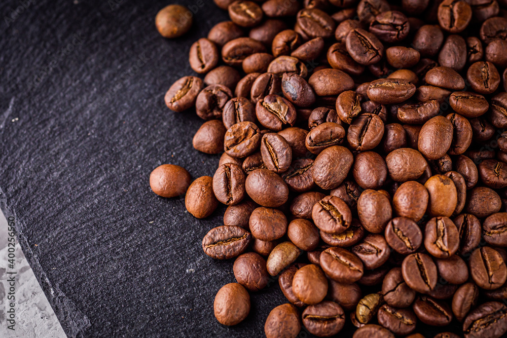Naklejka premium aromatic fresh coffee beans on a dark stone background