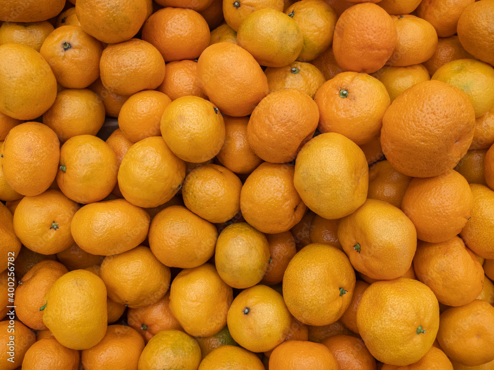 Background of a large number of orange mandarin (Citrus reticulata) fruits. Background from fruits on the showcase. Harvest orange mandarin. Background of a large number of orange mandarin (Citrus reticulata) fruits. Background from fruits on the showcase. Harvest orange mandarin.