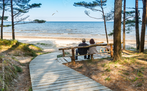 Happy couple of seniors are resting on wooden bench and  looking at the dista...