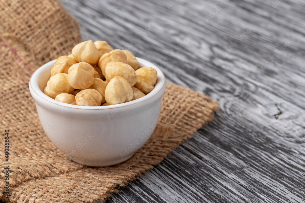 Peeled nuts in white bowl on black wooden table. Peeled nuts in white bowl on black wooden table.