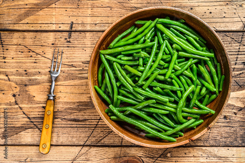 Cooked green beans in a wooden plate. wooden background. top view