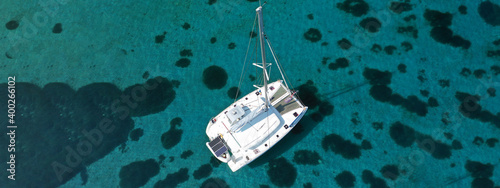 Aerial drone ultra wide photo of Catamaran sail boat anchored in tropical exotic bay with emerald crystal clear sea photo