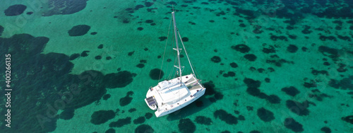 Aerial drone ultra wide photo of Catamaran sail boat anchored in tropical exotic bay with emerald crystal clear sea