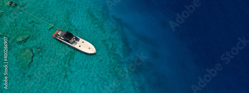 Aerial drone ultra wide photo of speed boat with wooden deck anchored in tropical exotic turquoise crystal clear sea bay