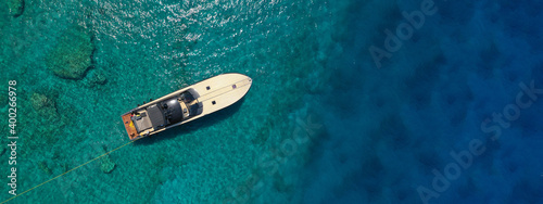 Aerial drone ultra wide photo of speed boat with wooden deck anchored in tropical exotic turquoise crystal clear sea bay © aerial-drone