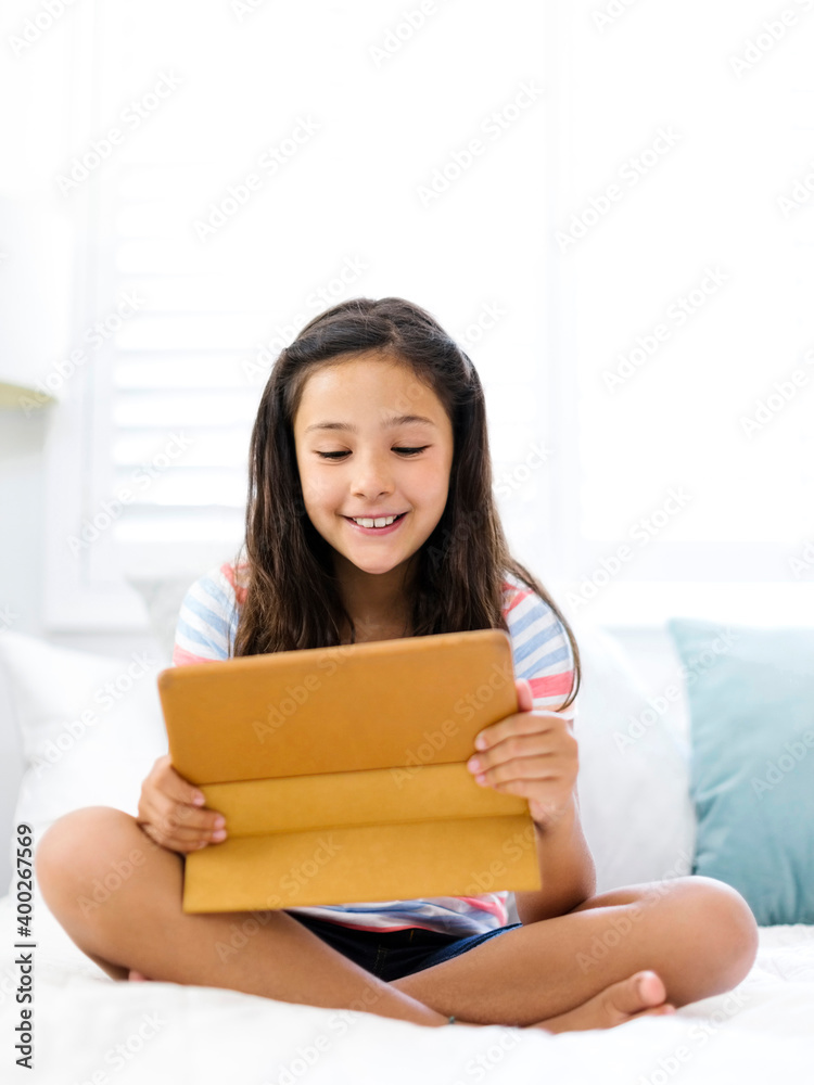 Smiling girl (10-11) sitting and watching tablet Smiling girl (10-11) sitting and watching tablet