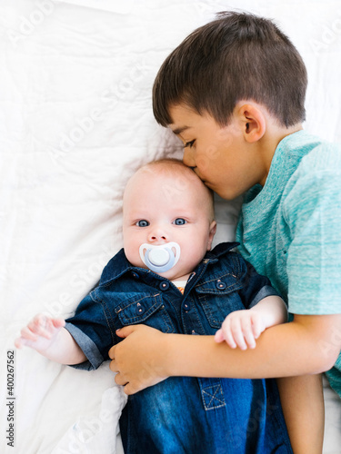 Portrait of boy (8-9) kissing his younger brother (12- 17 months) photo