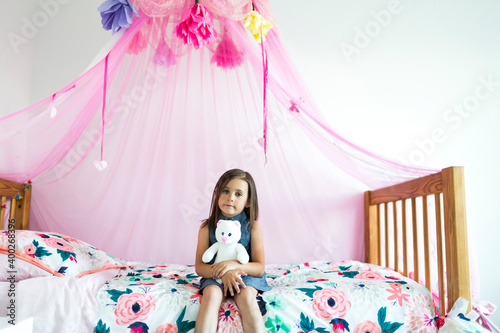 Girl (6-7) sitting on bed photo