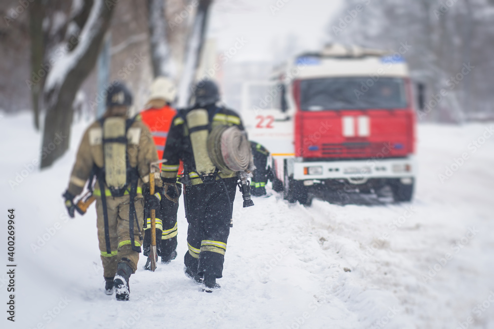 Group of fire men in uniform, firefighters with the fire engine truck fighting vehicle in the background, winter streets Group of fire men in uniform, firefighters with the fire engine truck fighting vehicle in the background, winter streets
