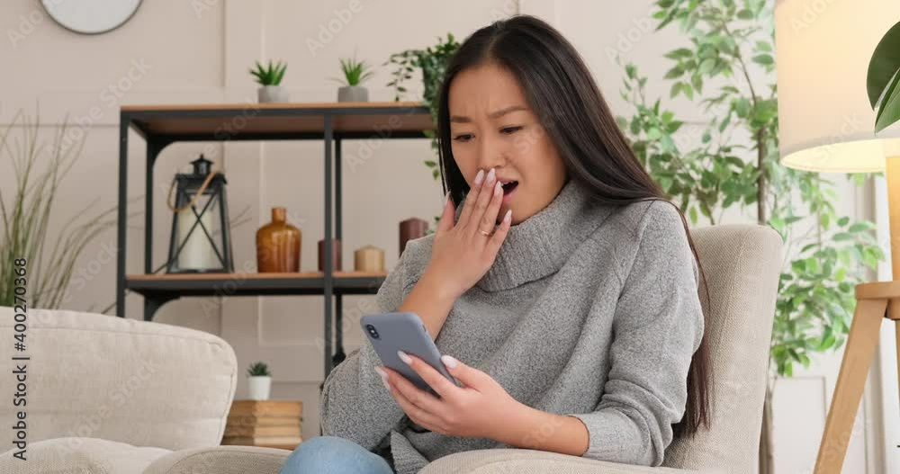 Woman amazed while text messaging using mobile phone at home Woman amazed while text messaging using mobile phone at home